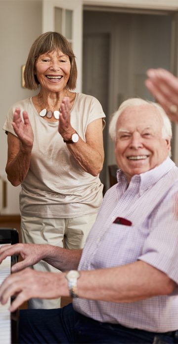Group of elderly people clapping hands for a male friend playing piano. Friends applauding senior man for playing piano.